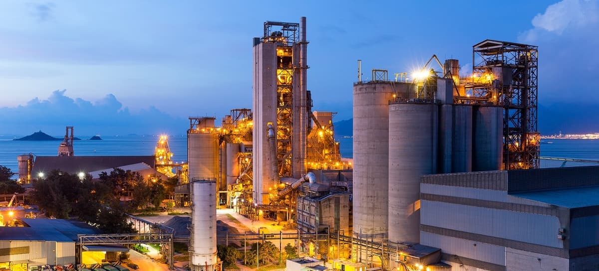 Grande instalação industrial com tanques, tubulações e luzes. 