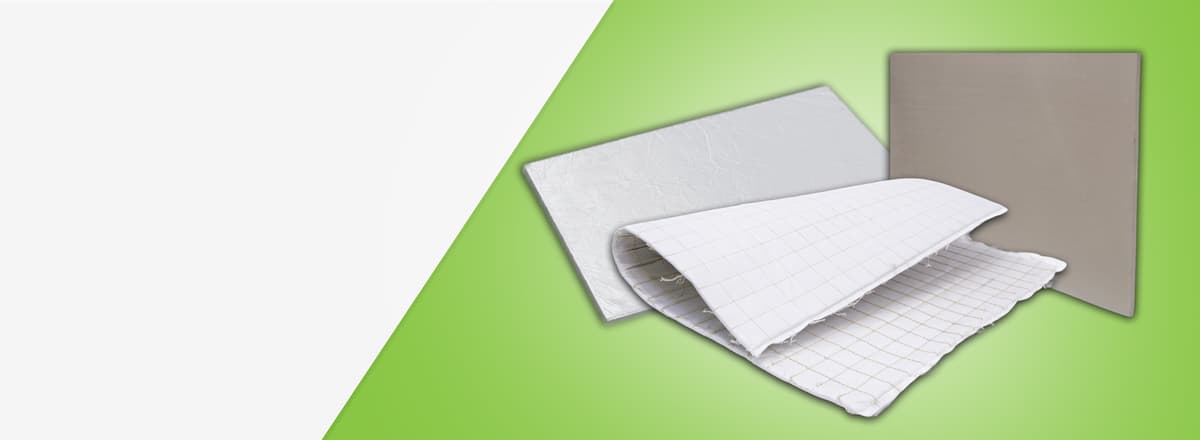 Três amostras de materiais de isolamento térmico: uma manta flexível branca acolchoada dobrada no centro e duas placas rígidas retangulares ao fundo.